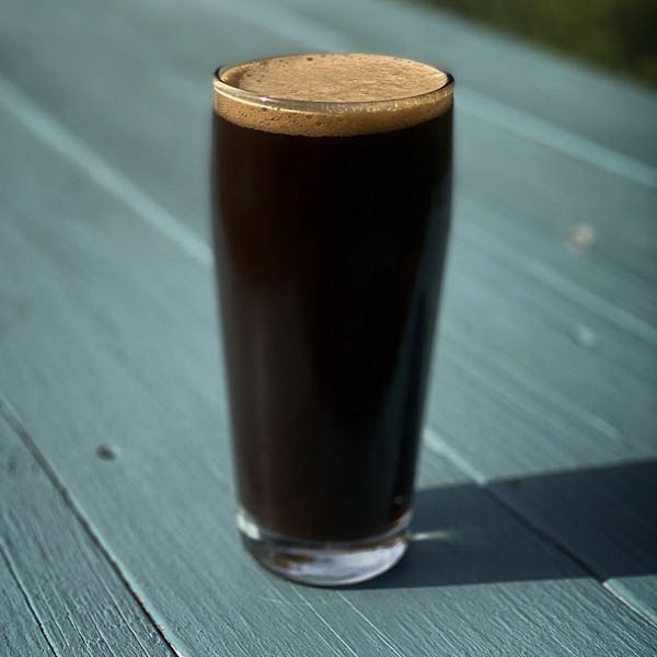 dar beer in pint glass on blue picnic table