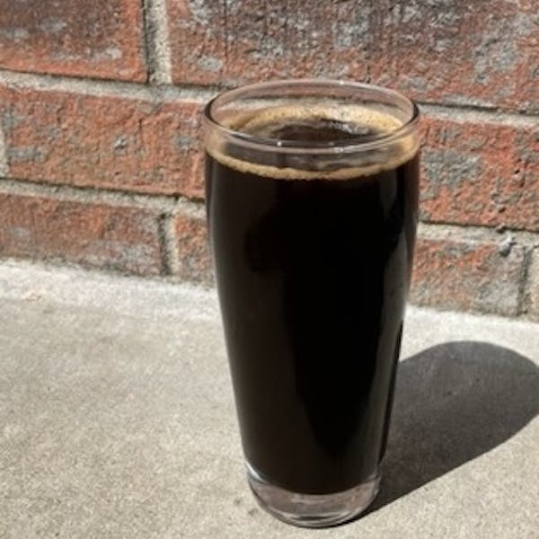 dark beer in a glass in front of brick wall
