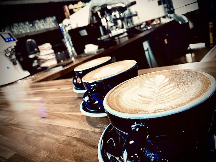 cafe2 three lattes in blue ceramic mugs on a wooden bar