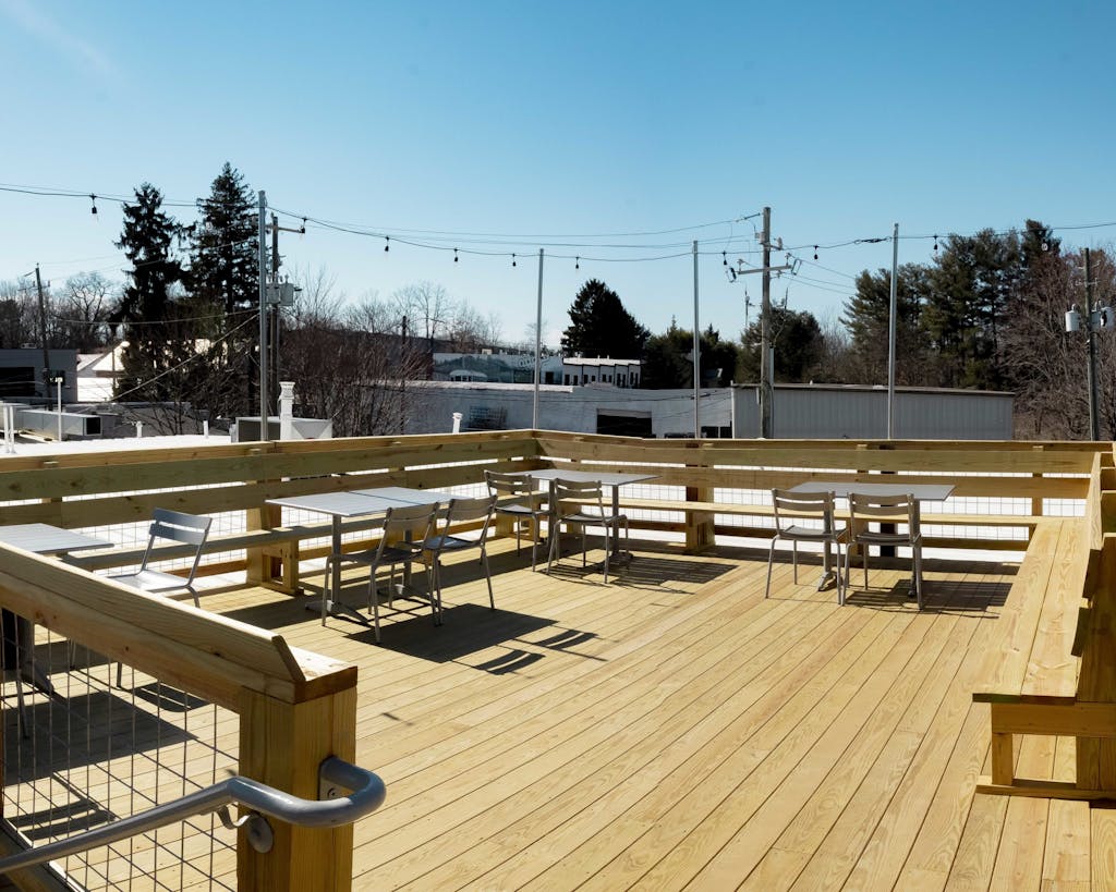 wooden rooftop deck with tables and chairs