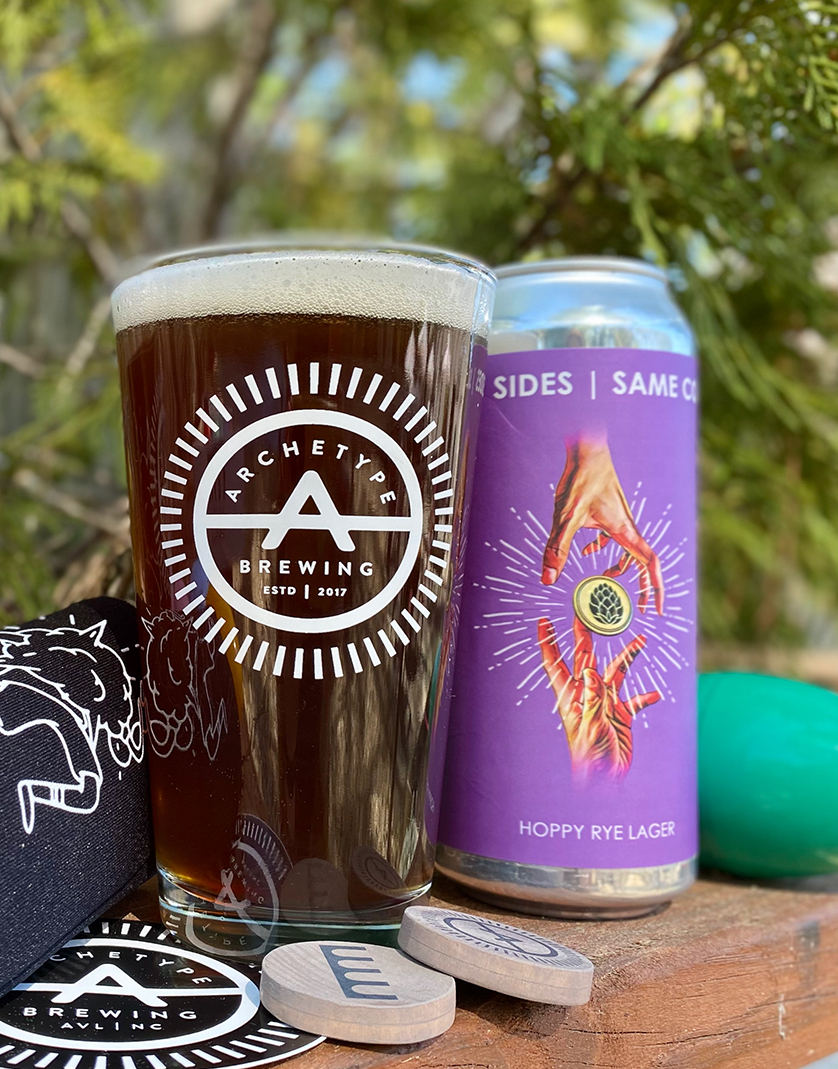 Archetype pint glass with dark beer next to purple can