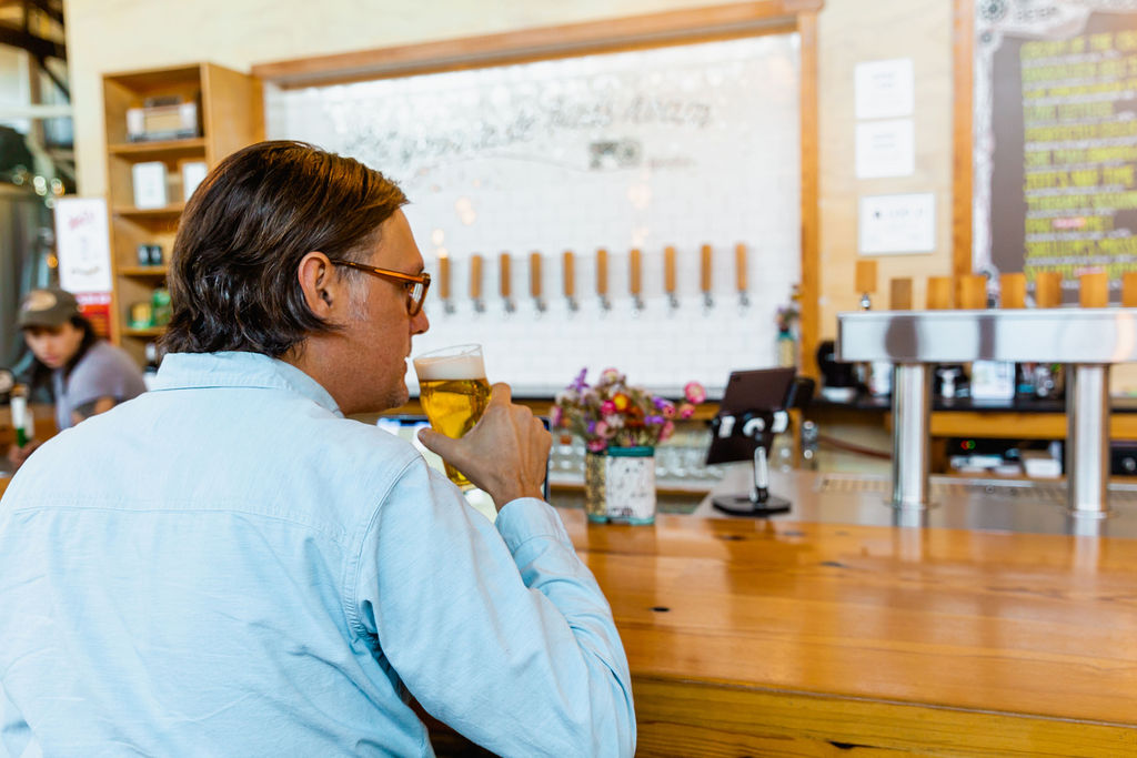 A guest drinks a beer sitting at the bar