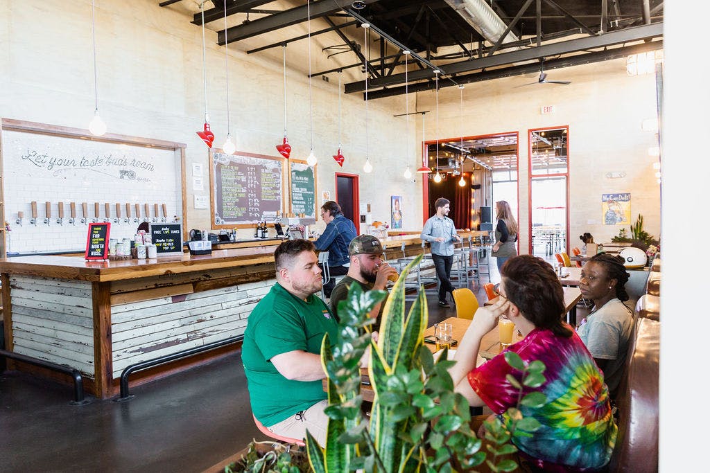 people enjoy beer at tables inside a taproom