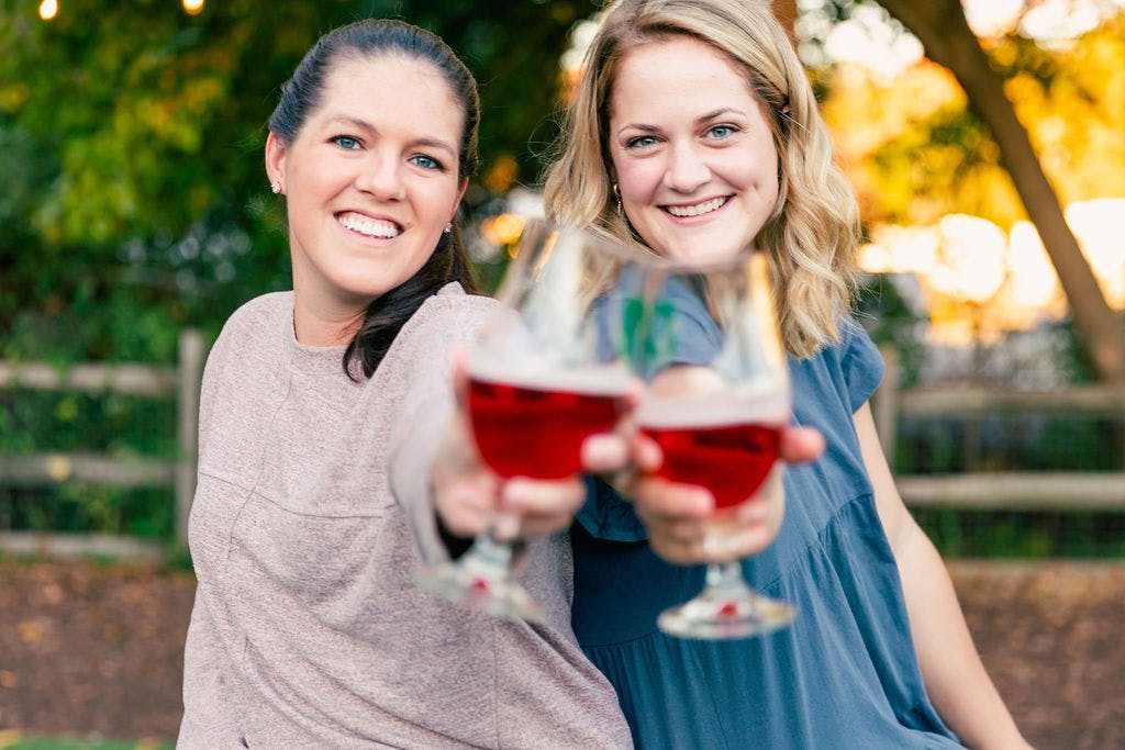 two women hold up glasses of beer 
