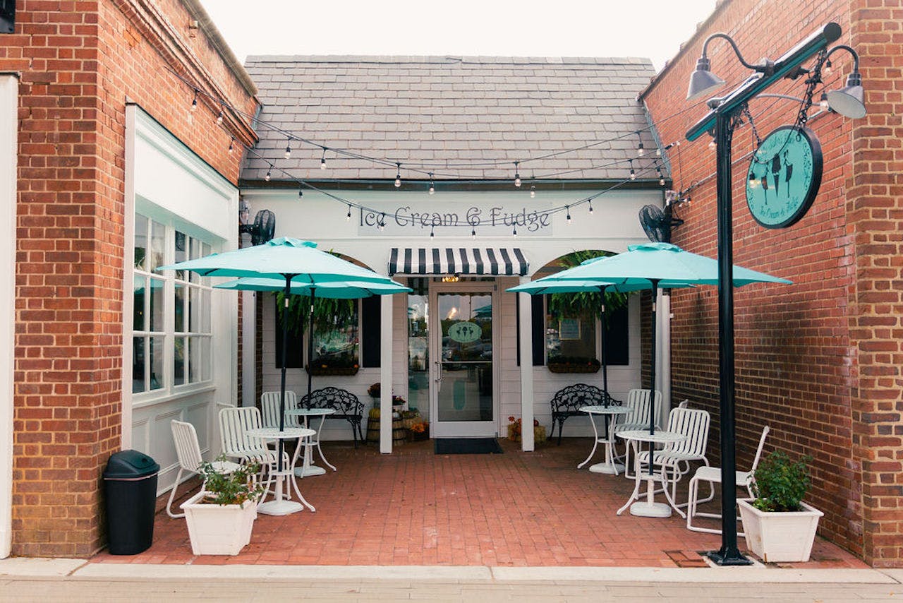 Patio of a taproom with white chairs and green umbrellas