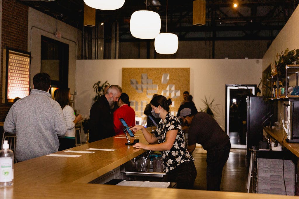 Bartender serves beer in a dimly lit taproom with a wooden bar
