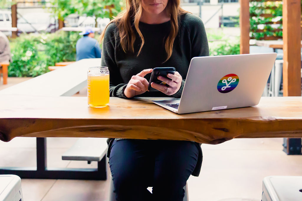 woman sitting at laptop and checking her phone