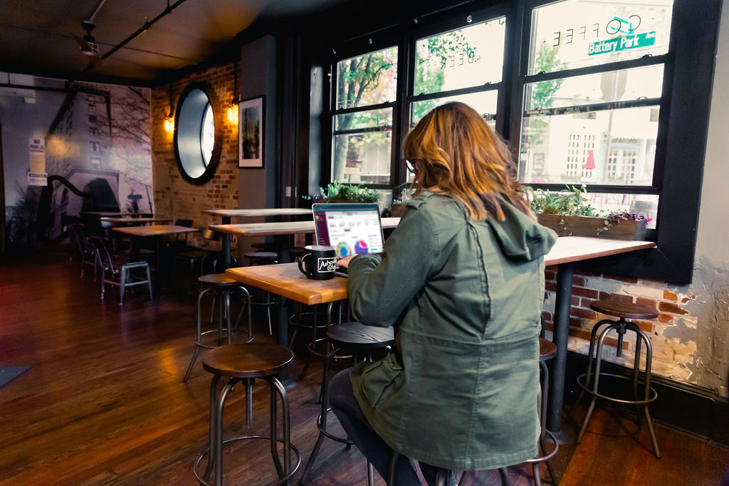 a woman works on her computer at a table in a bar