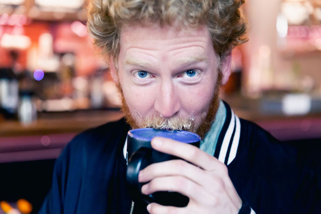A man drinks a beer out of a glass