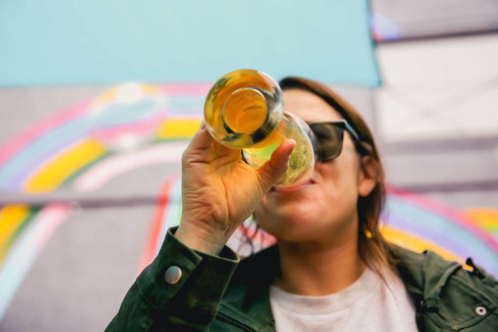 a woman drinks her beer from a pint glass