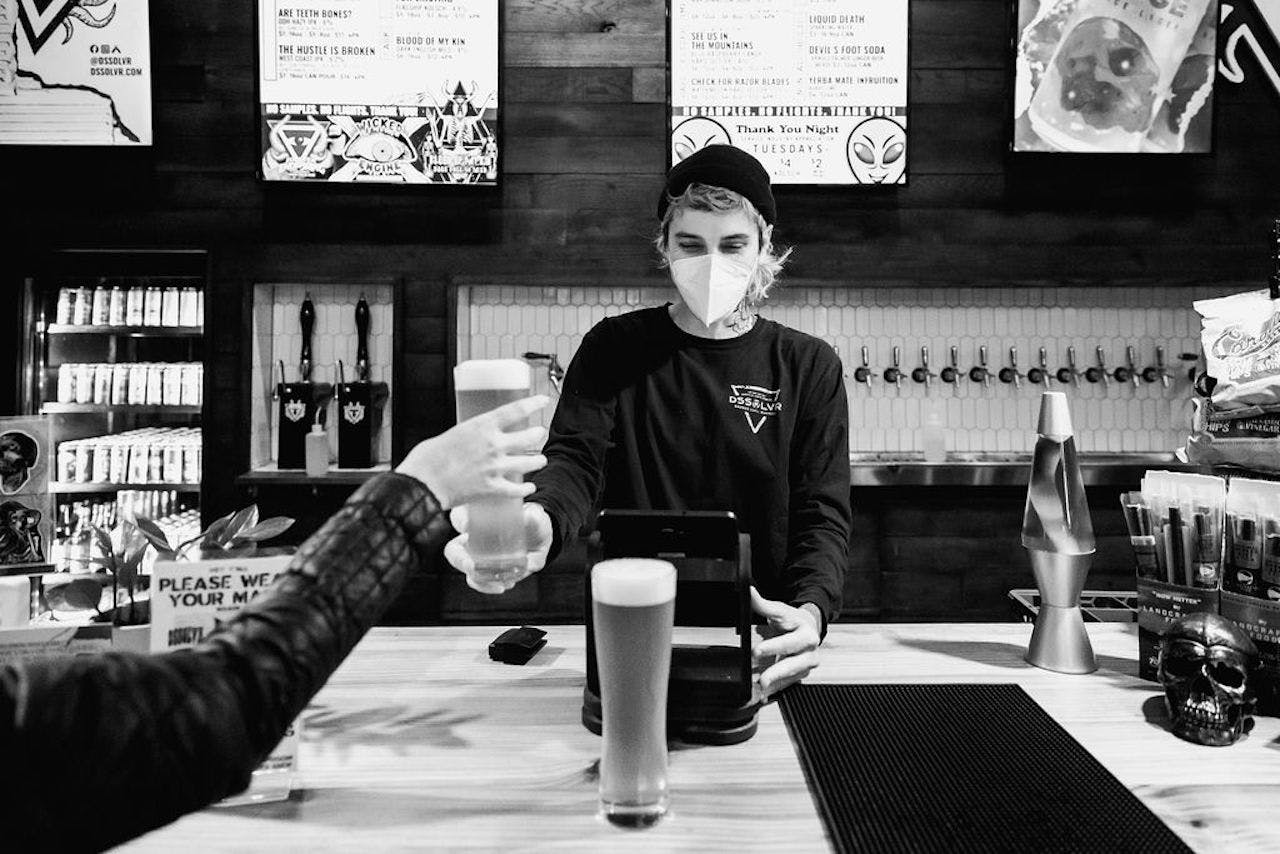 A bartender serves beer from behind a bar 