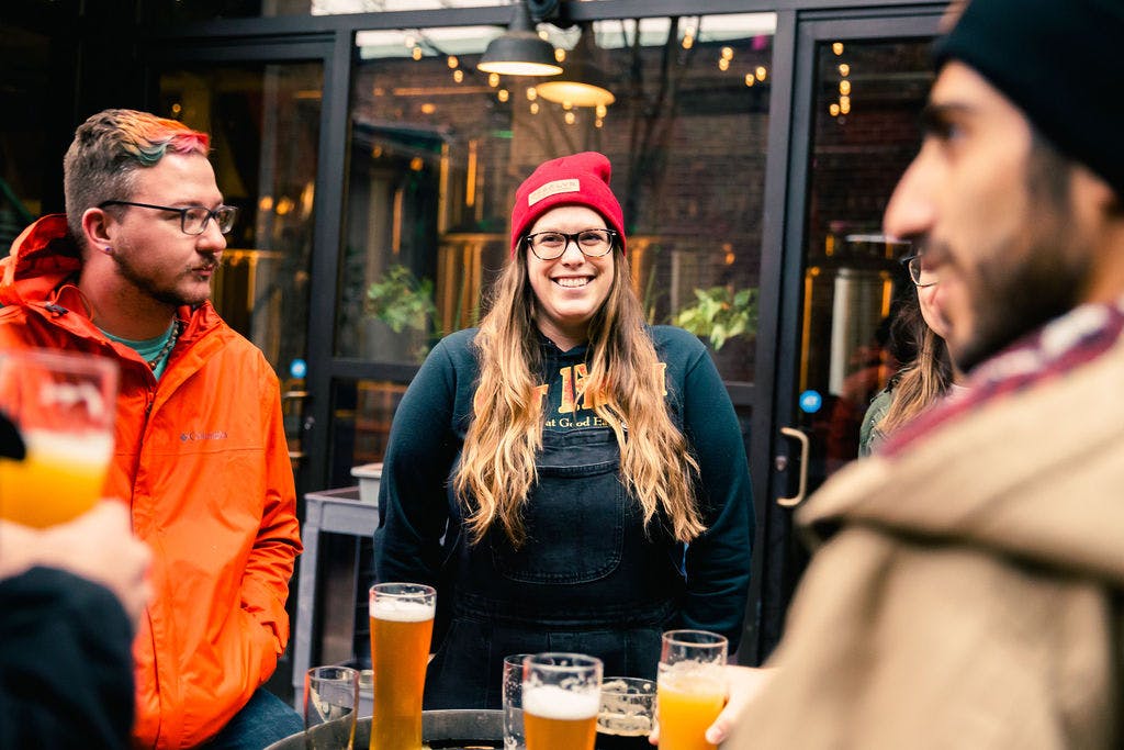 people enjoying beers around a barrel table