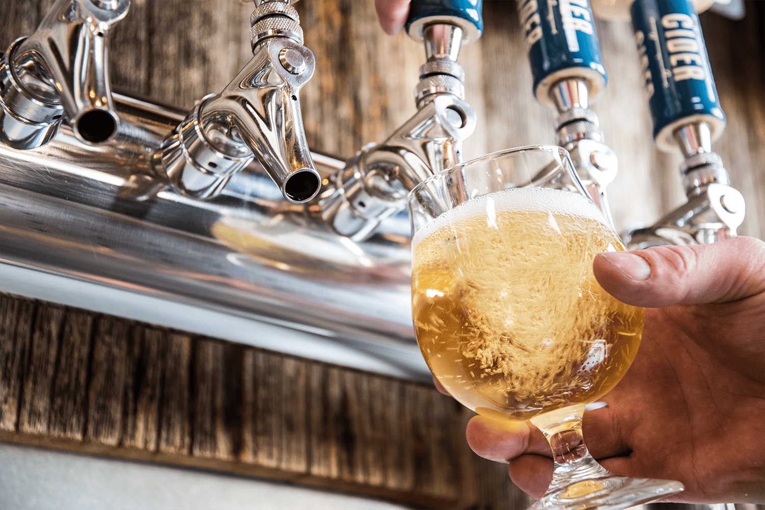 Cider being poured into a glass from a tap