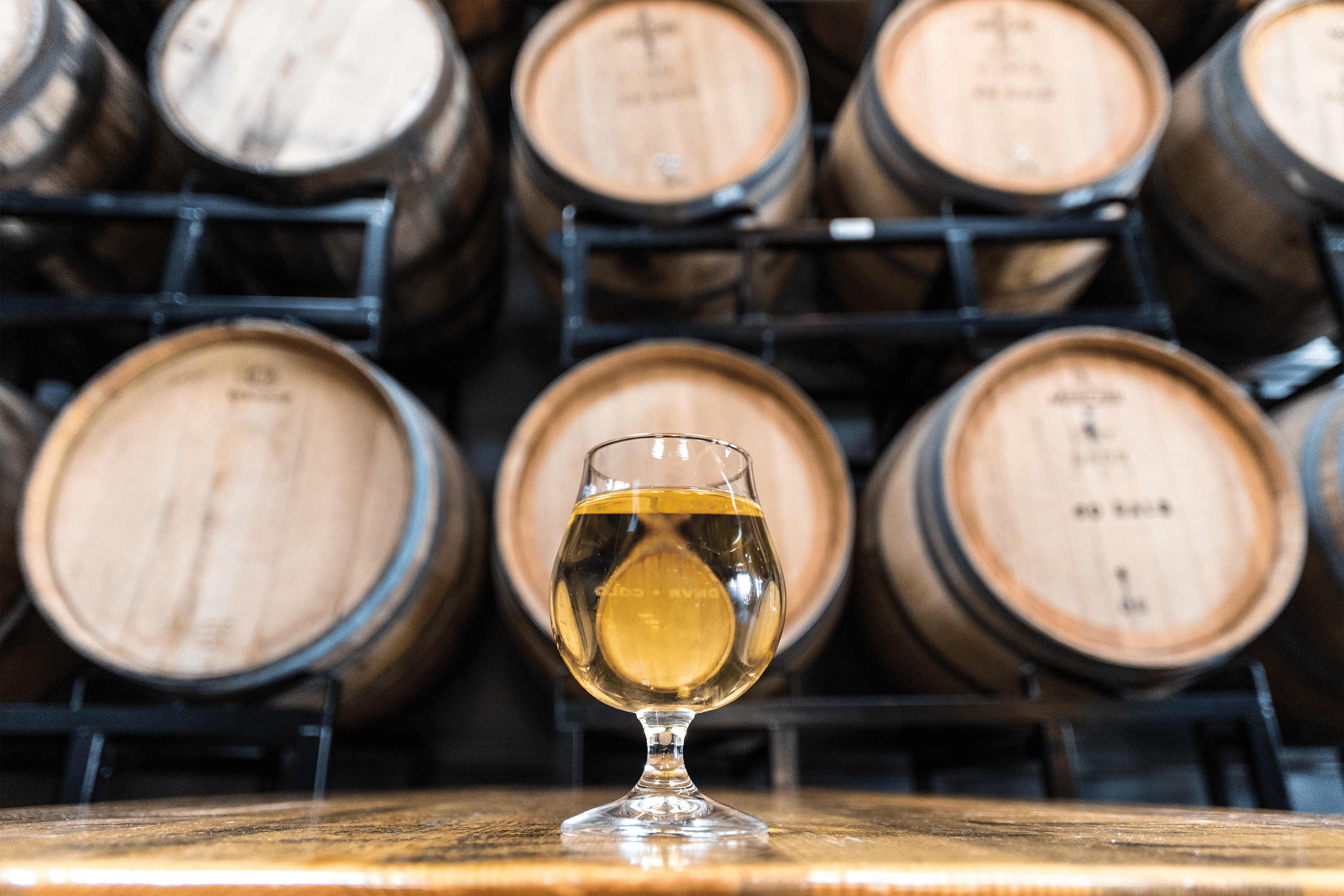 beer in a tulip glass in front of barrels 