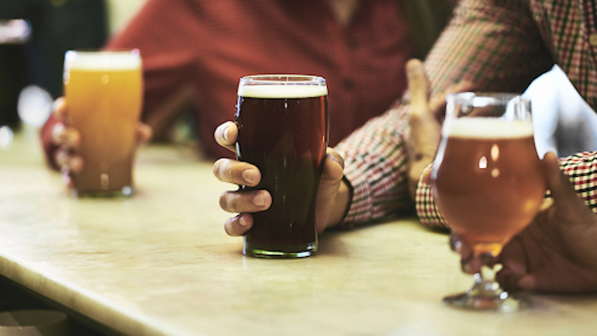 Hand holding pint of beer on a bar