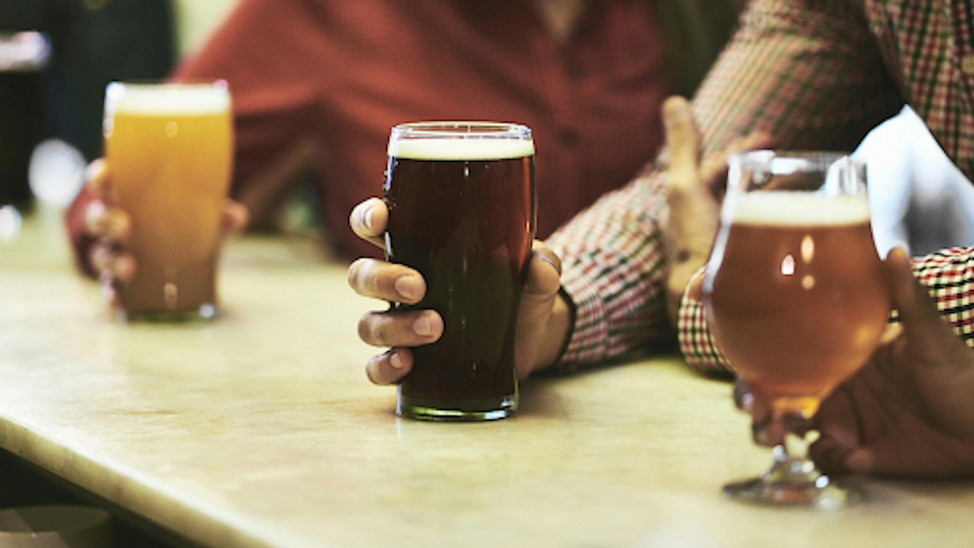 Hand holding pint of beer on a bar