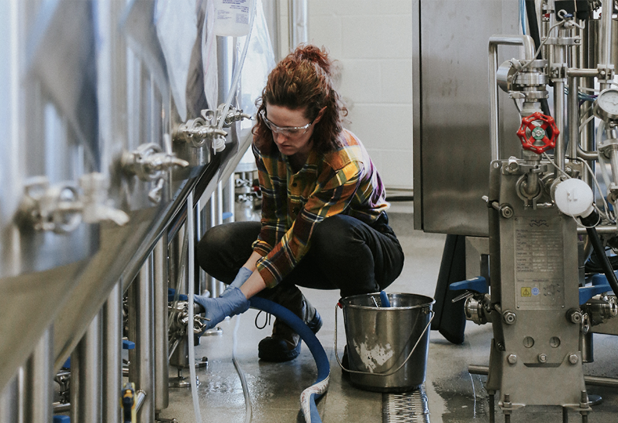 a brewer adjusts the brewing equipment in a brewery