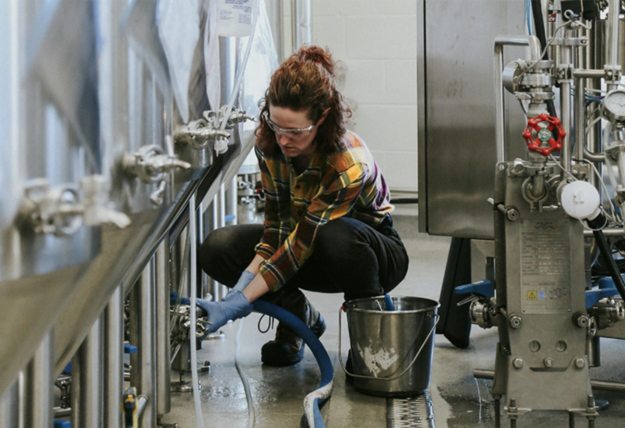 a brewer adjusts the brewing equipment in a brewery