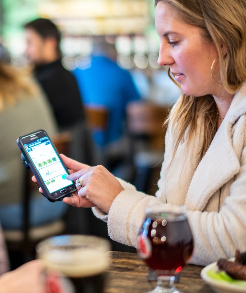 Person signing check at table, after adding to the donation feature within Arryved POS