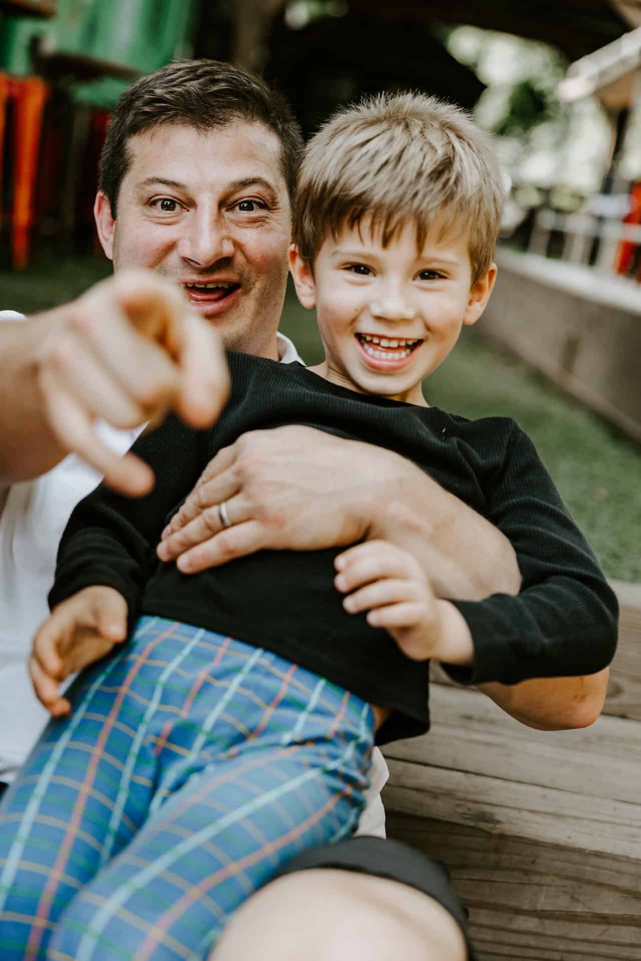 Babycat Brewery owner, Sam, holds his sone and points at the camera