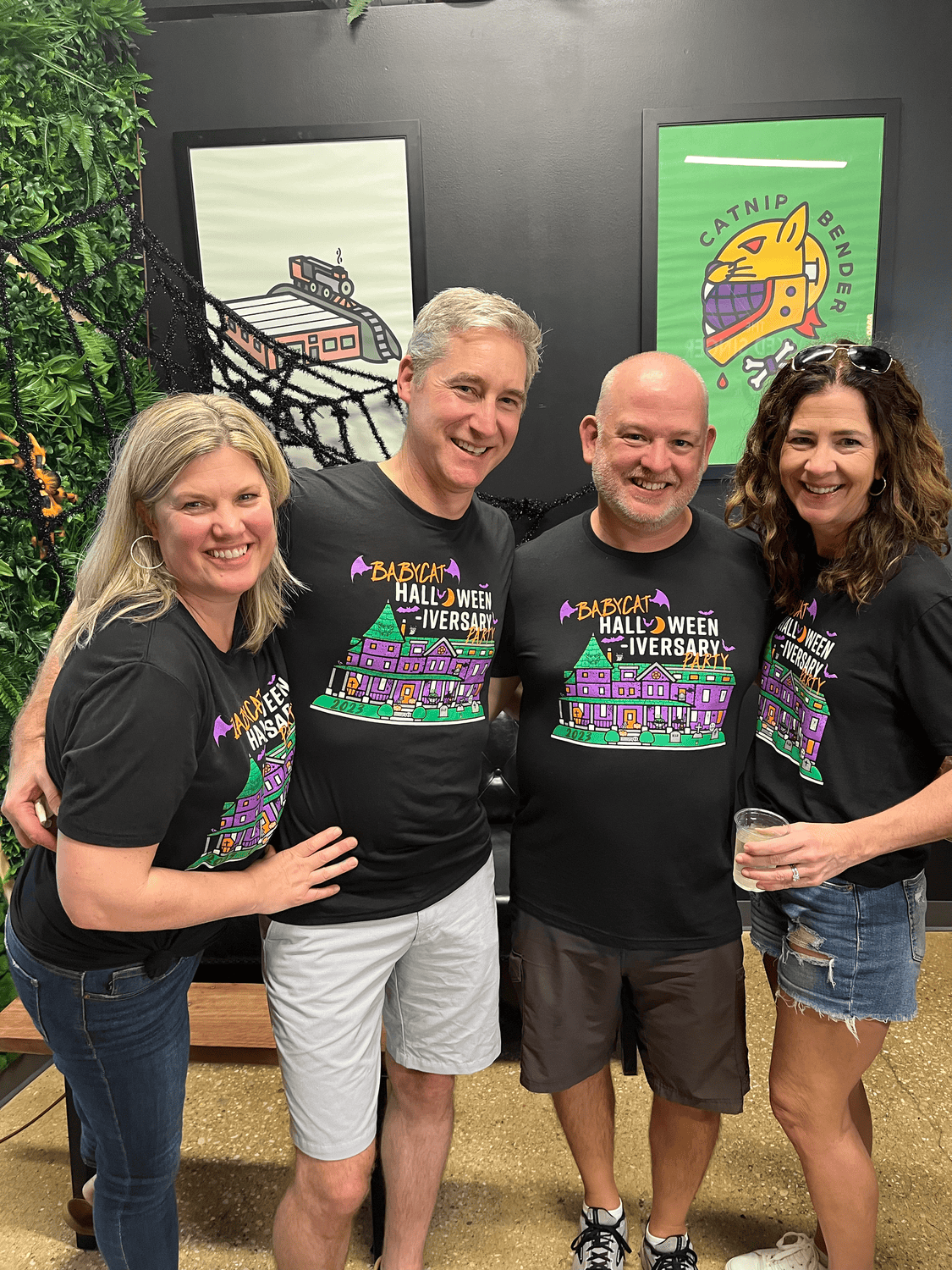 a group of four people standing together in matching halloween t-shirts
