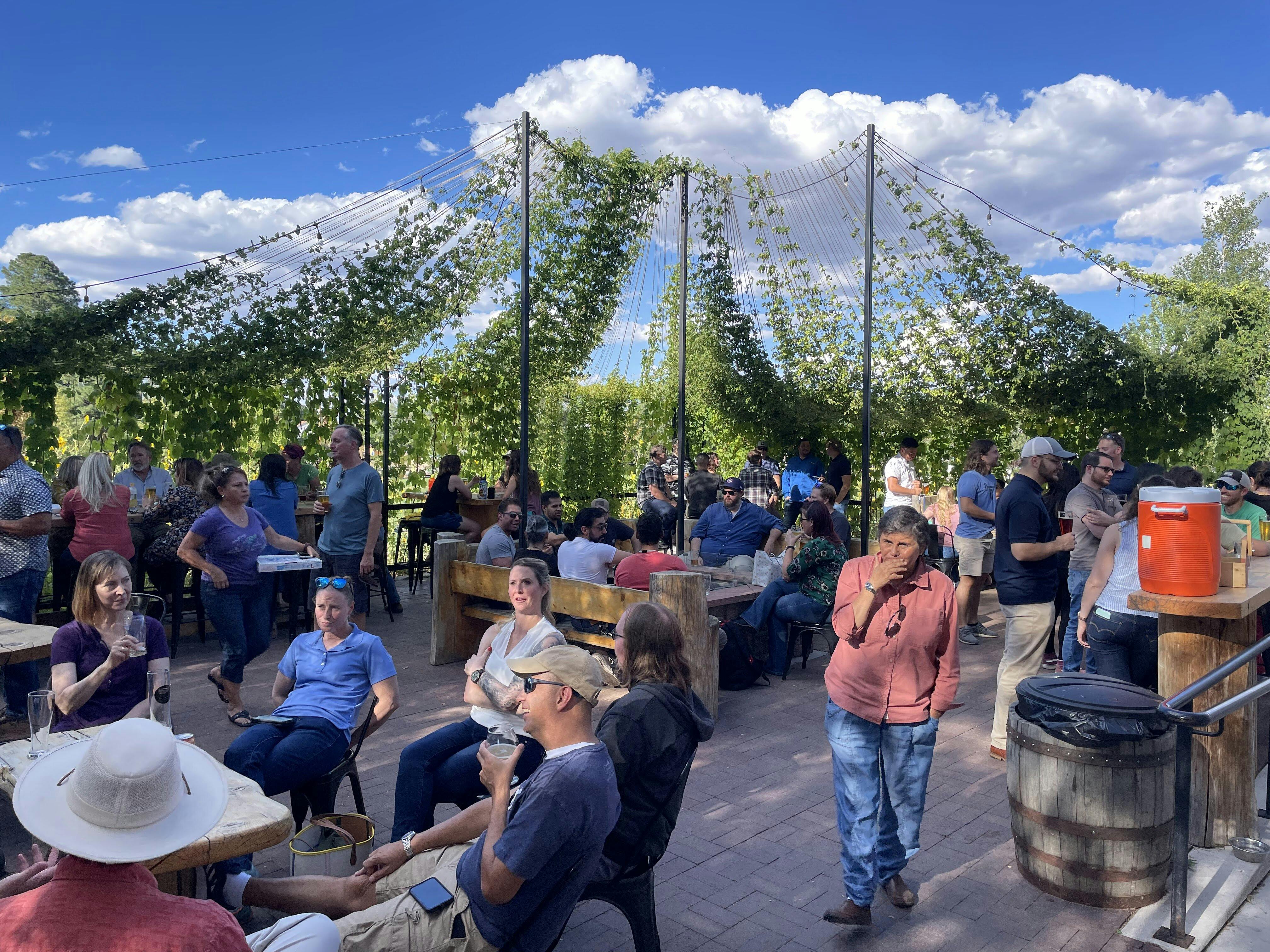 A crowded brewery patio with guests on a sunny day