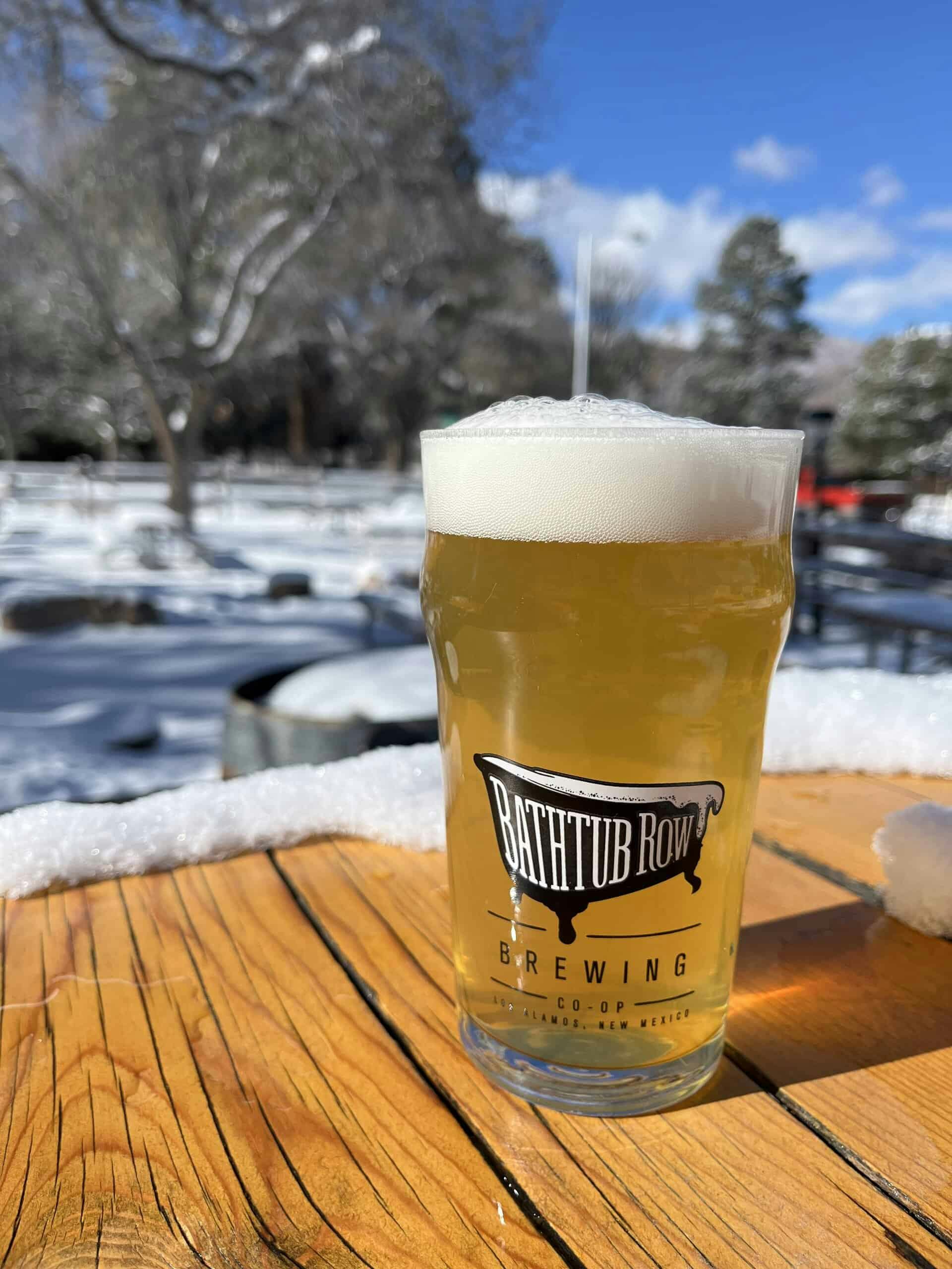 Pint glass of Bathtub Row Brewing outside on a wooden table in the snow