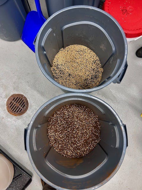 two large garbage cans filled with roasted malts