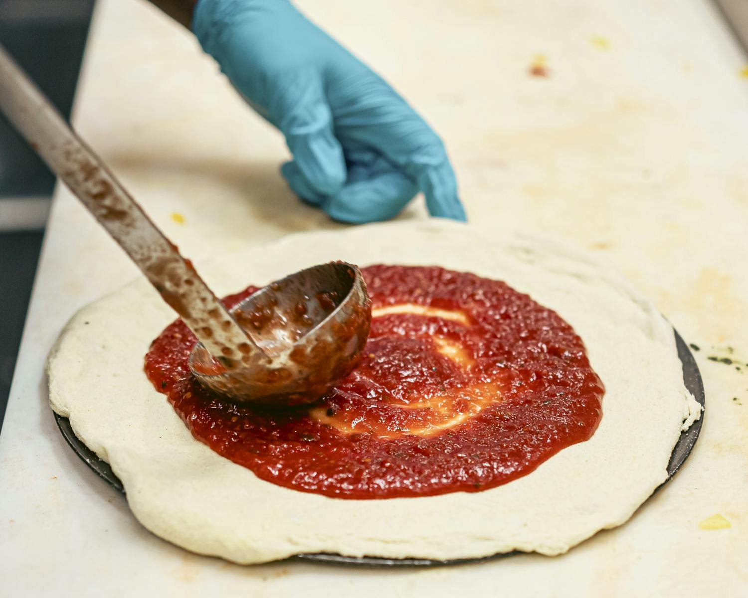 pizza with sauce being spread