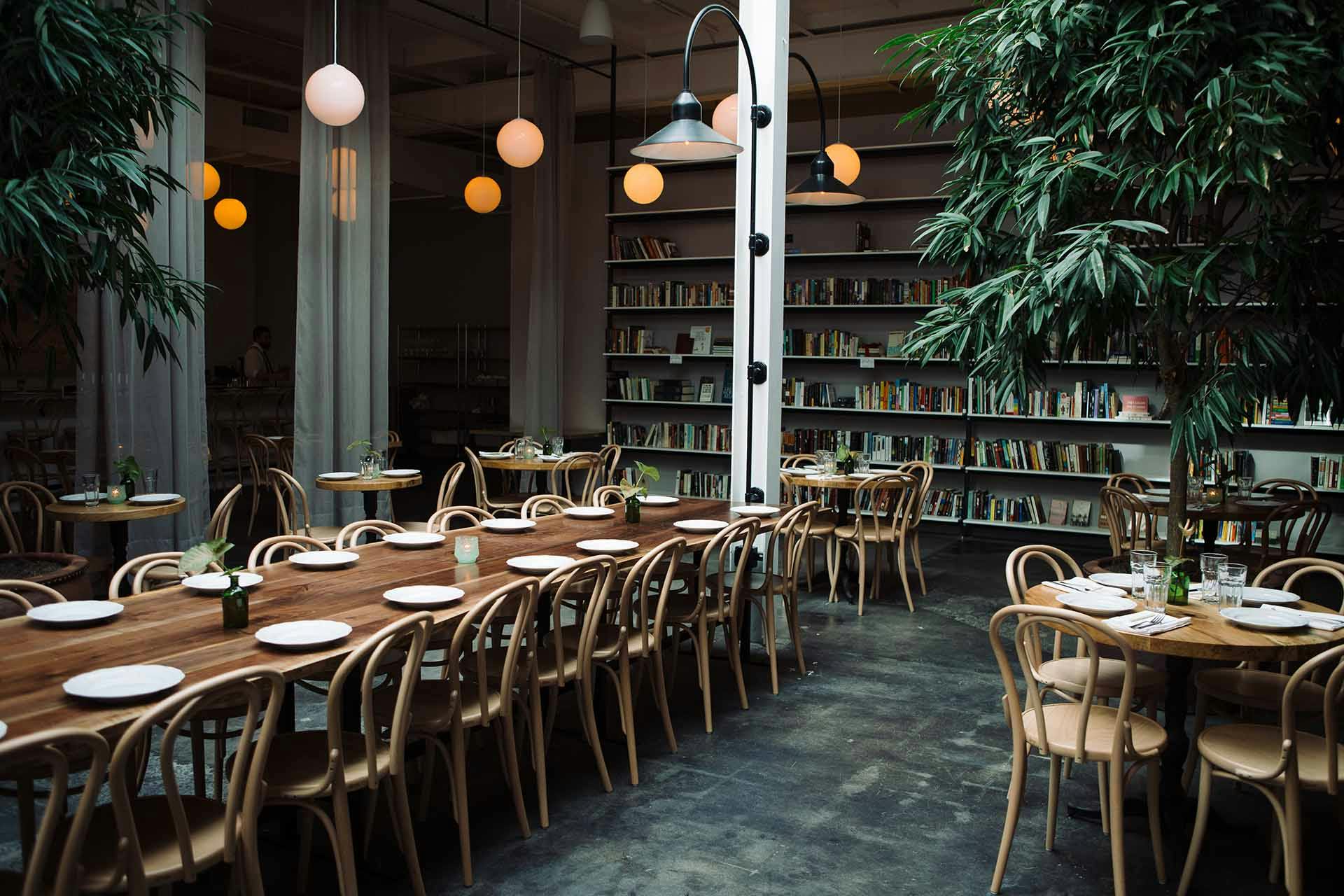 Long set tables in taproom with plants and soft globe lighting
