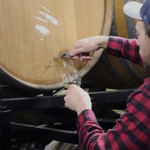 Troy Casey pulling a nail from a wine barrel at Casey Brewing and Blending's Barrel Cellar