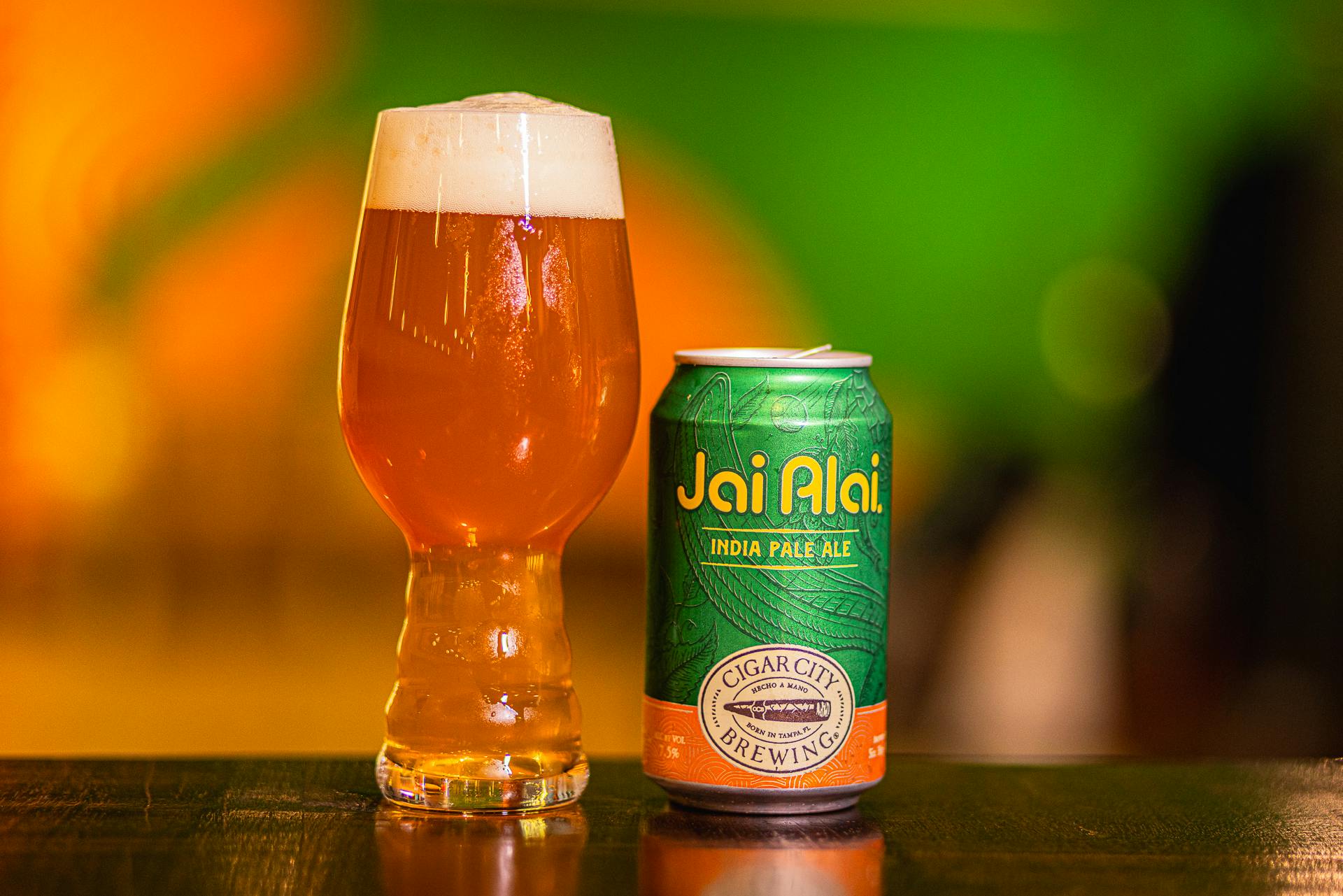 CCB_Website-36 A can of Jai Alai IPA sits on a table next to a glass full of beer.