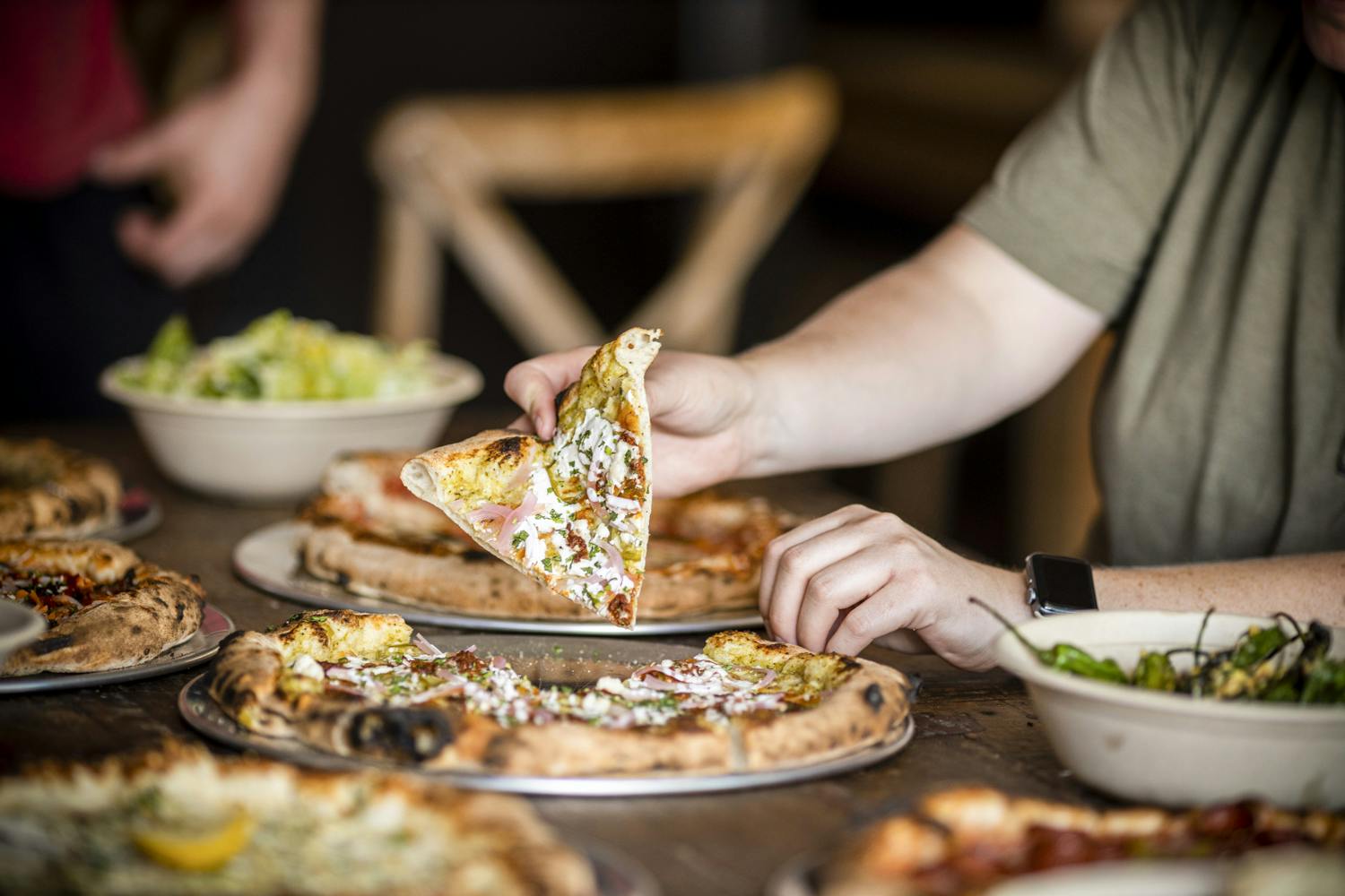 Commonwealth Brewing Company a guest eats a slice of pizza