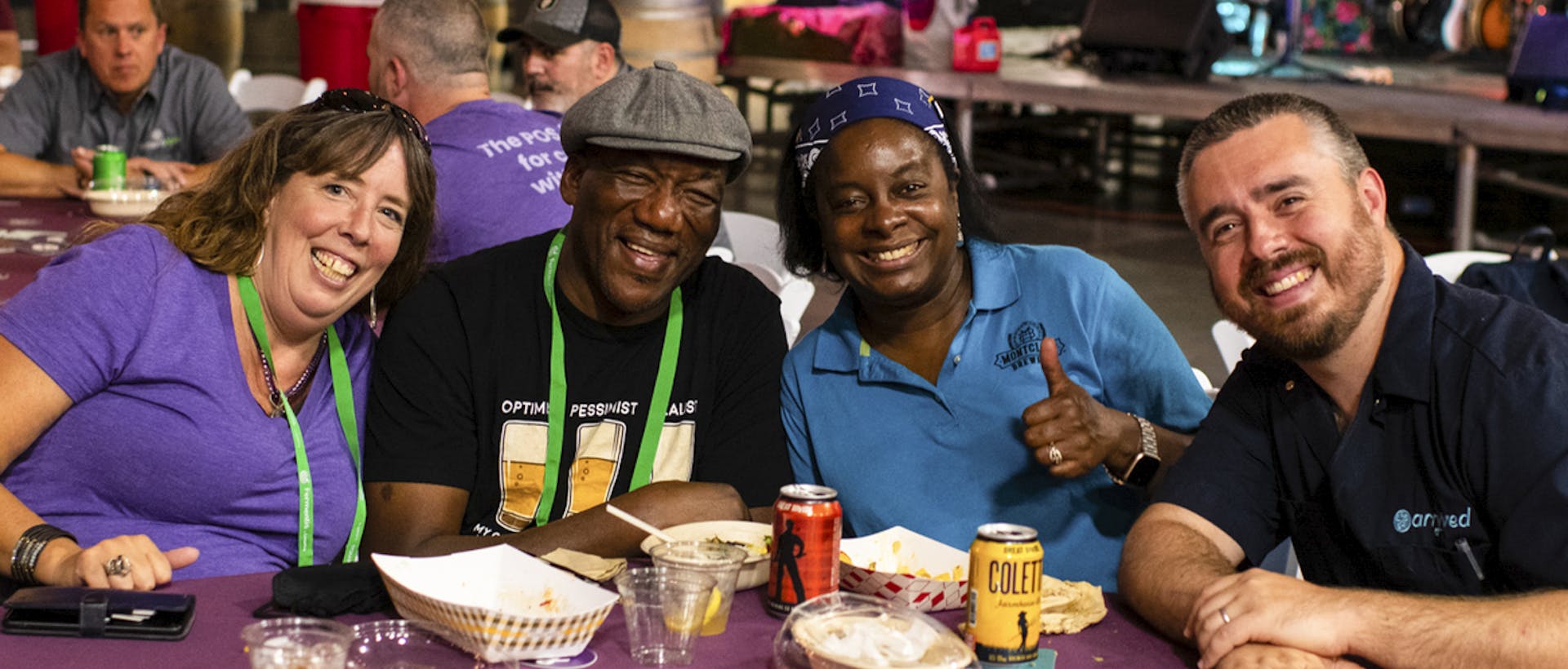 4 people at a table smile with food and beer dishes