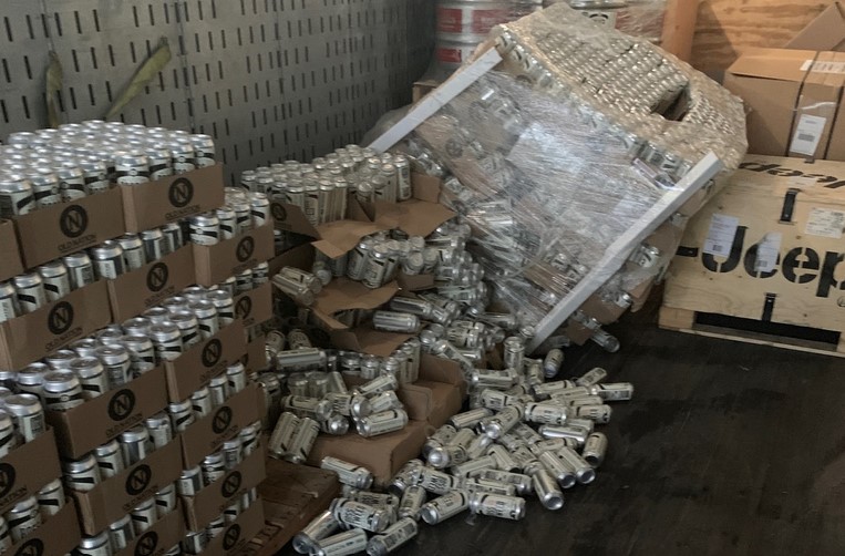 A fallen stack of beer with cans lying on the floor