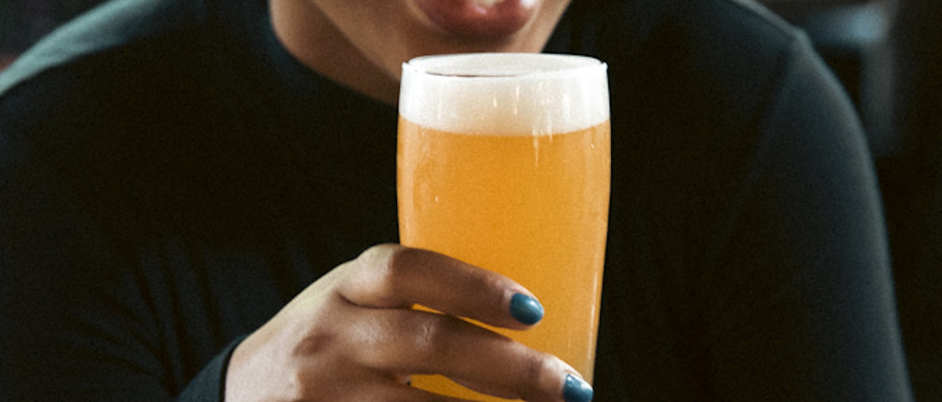 a woman smiles and enjoys a glass of beer