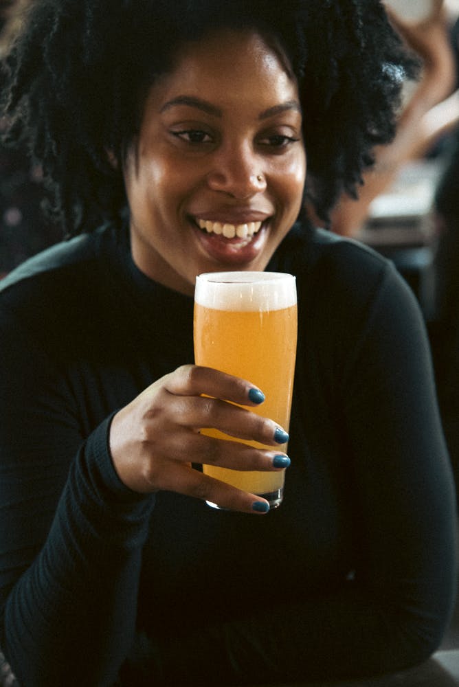 a woman smiles and enjoys a glass of beer