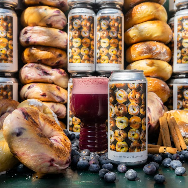 cans and bagels stacked with purple beer in glass