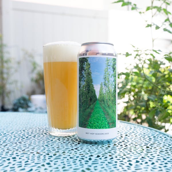 beer can on blue table with hazy beer in glass