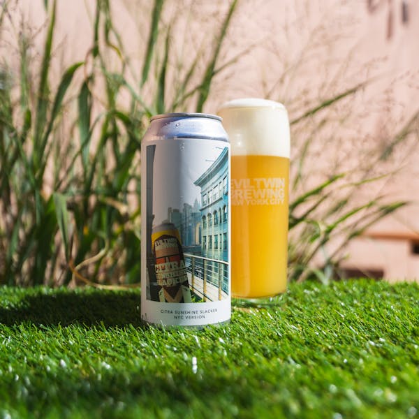 hazy beer in glass sitting on turf with beer can