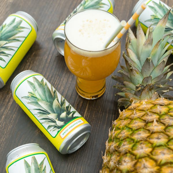 pineapple laying with beer cans and hazy golden beer