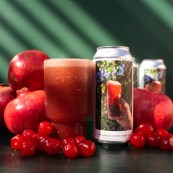 pink beer with beer can. pomegranate, cherries surrounding.