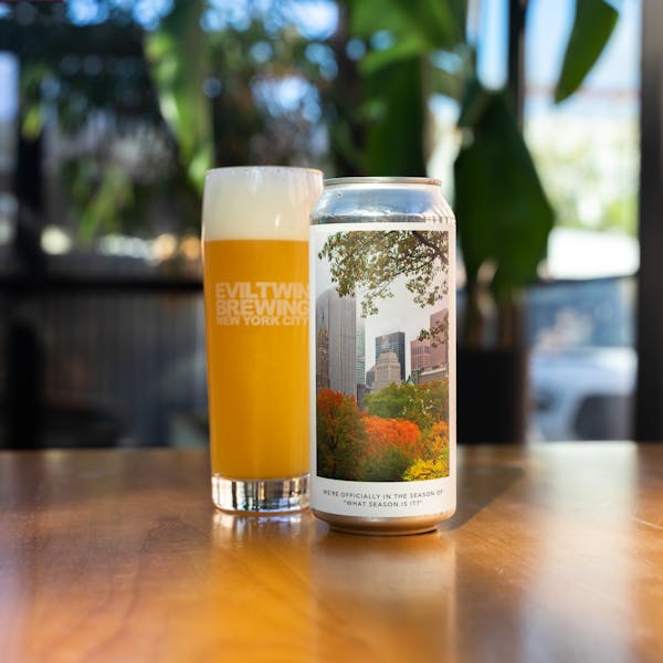 glass of hazy triple IPA on table with can