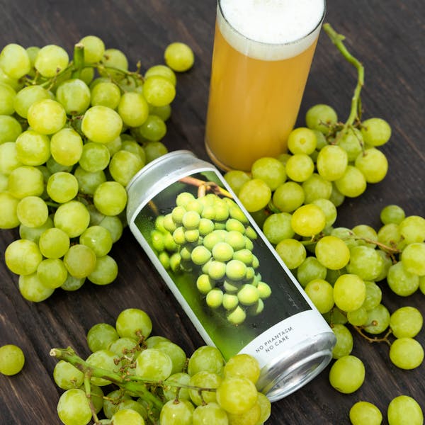 yellow beer in glass on table with grapes