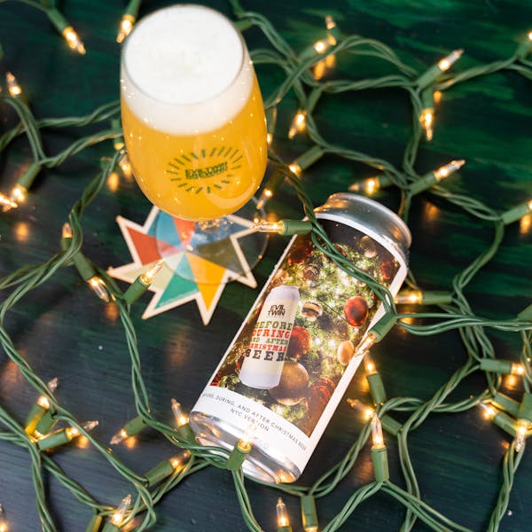 can laying in holiday lights with yellow beer in glass