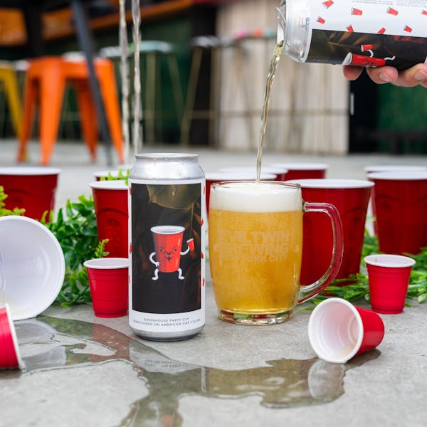 yellow beer in glass on concrete with party cups