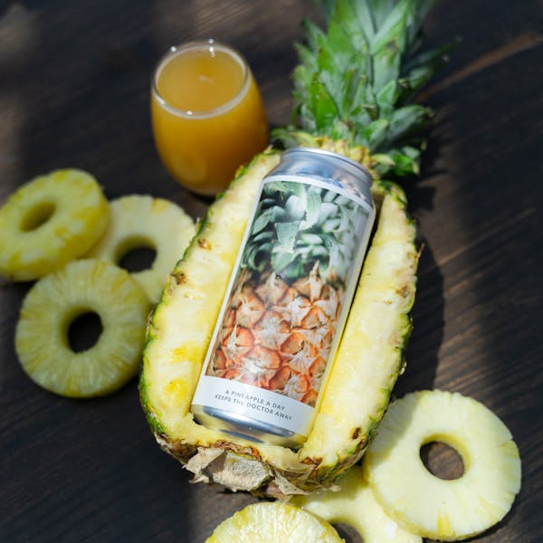 yellow beer in glass on table with can inside pineapple