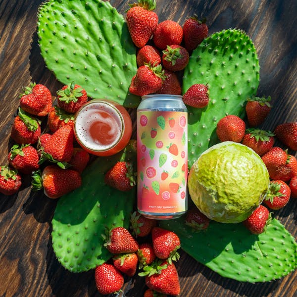 pink beer in glass on table with prickly pear, strawberries