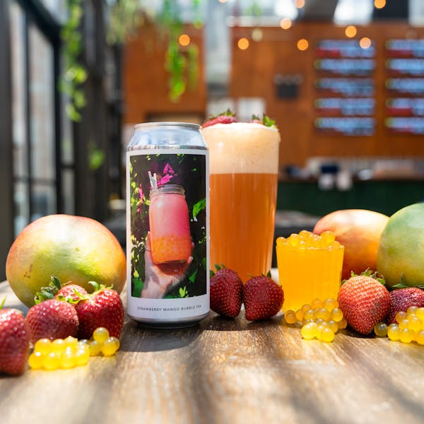pink beer in glass on table with fruit and bubble tea