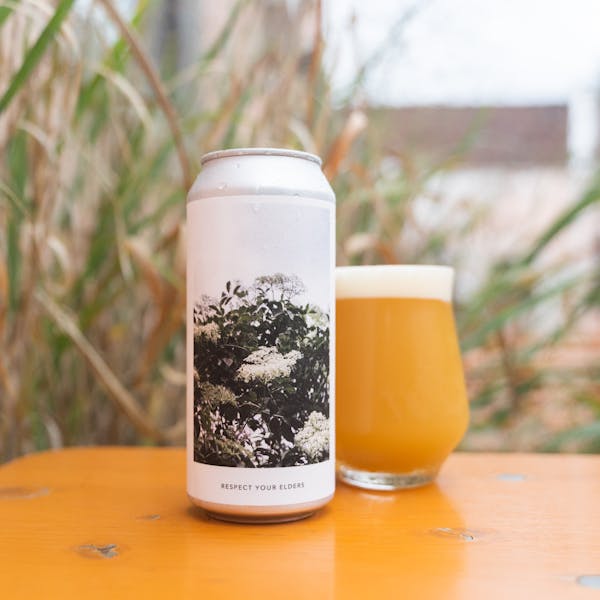 hazy beer in glass with can near grass